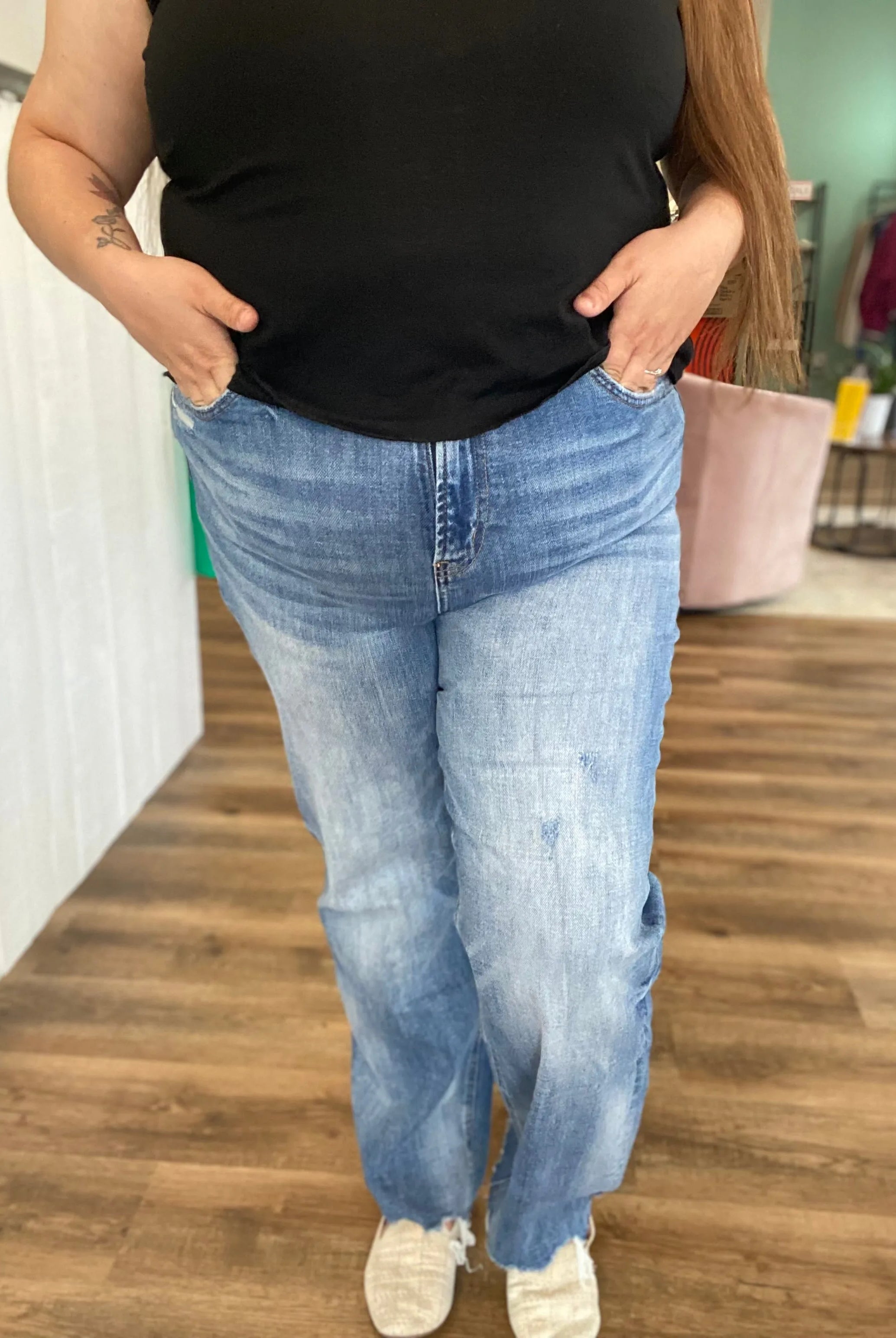 Person wearing blue jeans and a black top in an indoor setting