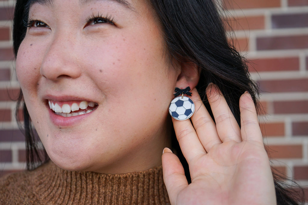 Shop Bow Soccer Ball Earrings- at Ruby Joy Boutique, a Women's Clothing Store in Pickerington, Ohio