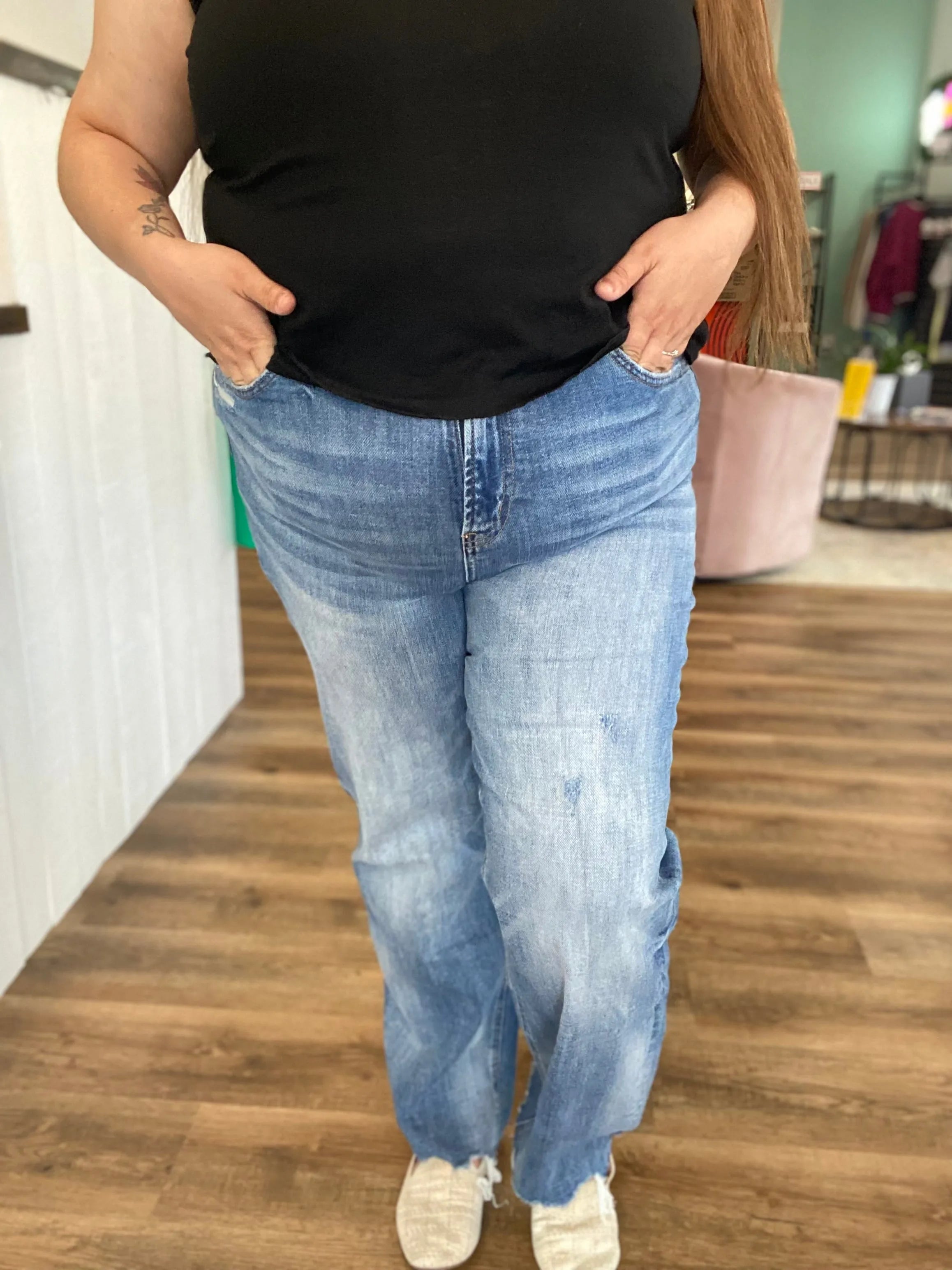 Person wearing blue jeans and a black top in an indoor setting